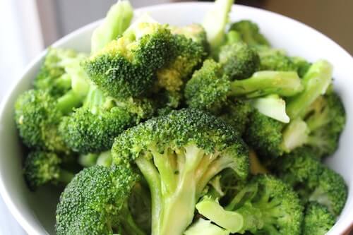 A white bowl with broccoli inside