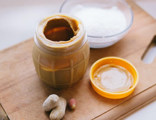 A jar of peanut butter on a cutting board