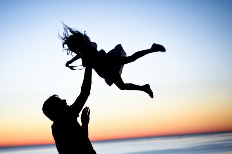 dad playing with daughter on the beach